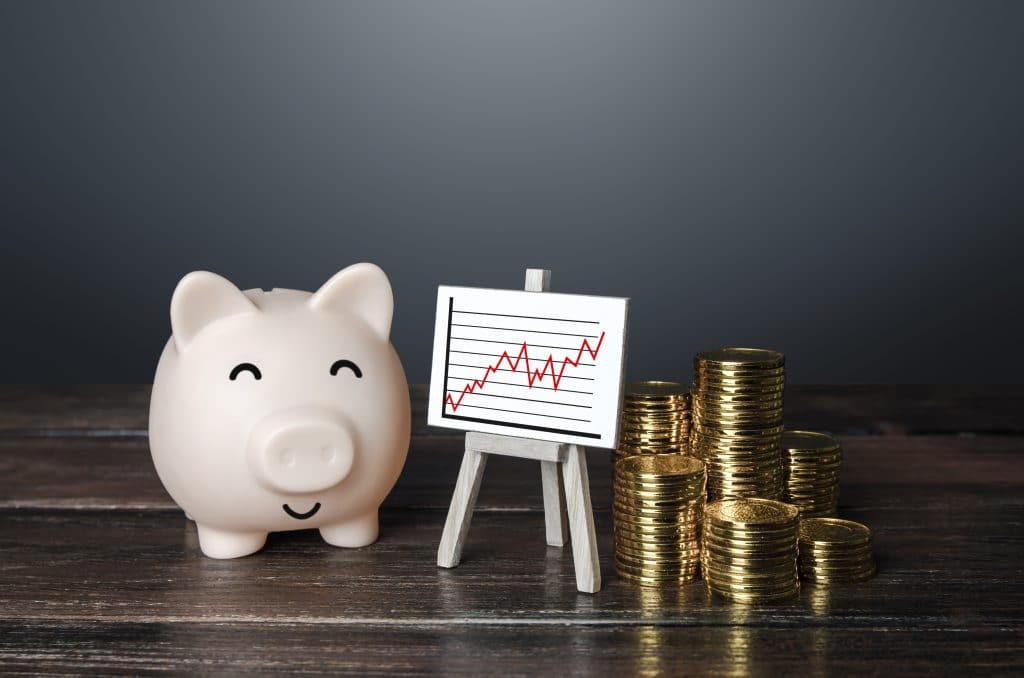 A smiling piggy bank with a stack of coins and a chart showing an increase in investment or money.