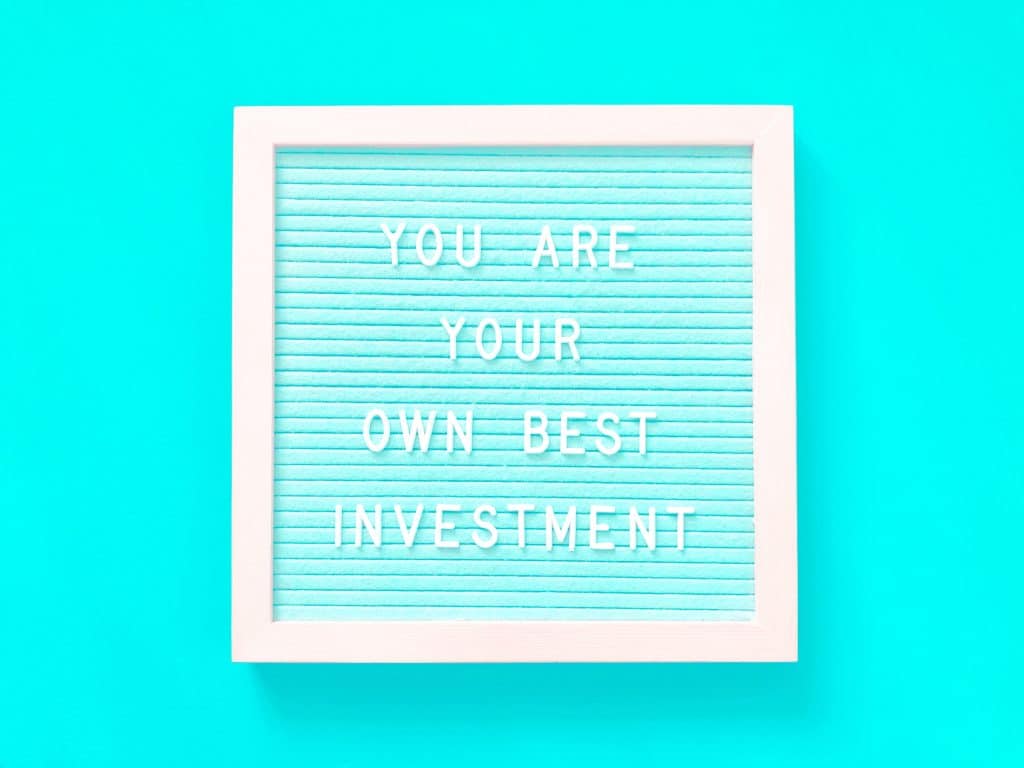 A white framed board with the quote “You are your own best investment”